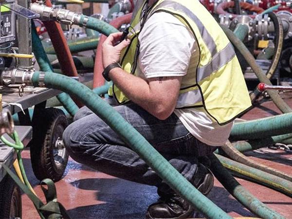 A worker monitors the operation of green chemical hose.