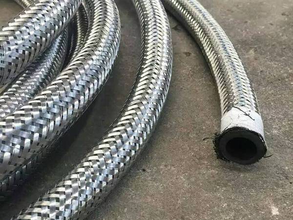 Braided stainless steel armoured hoses are placed on the ground.