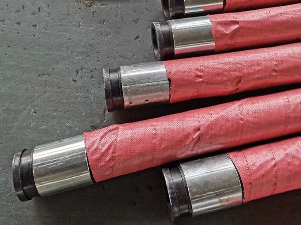 Concrete pump rubber hoses wrapped in red packaging paper placed on the factory floor.